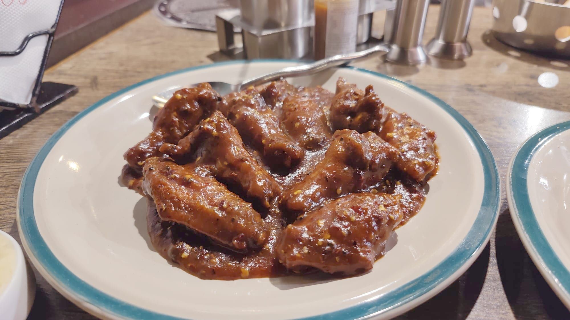 A plate of chicken wings in a dark, glossy barbecue sauce.